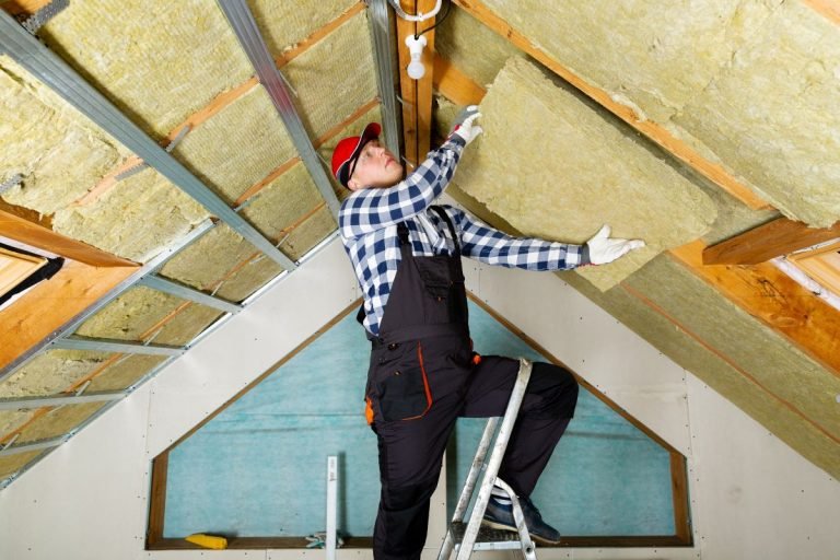 A man installs insulation on a roof, demonstrating the insulation installation service in action.
