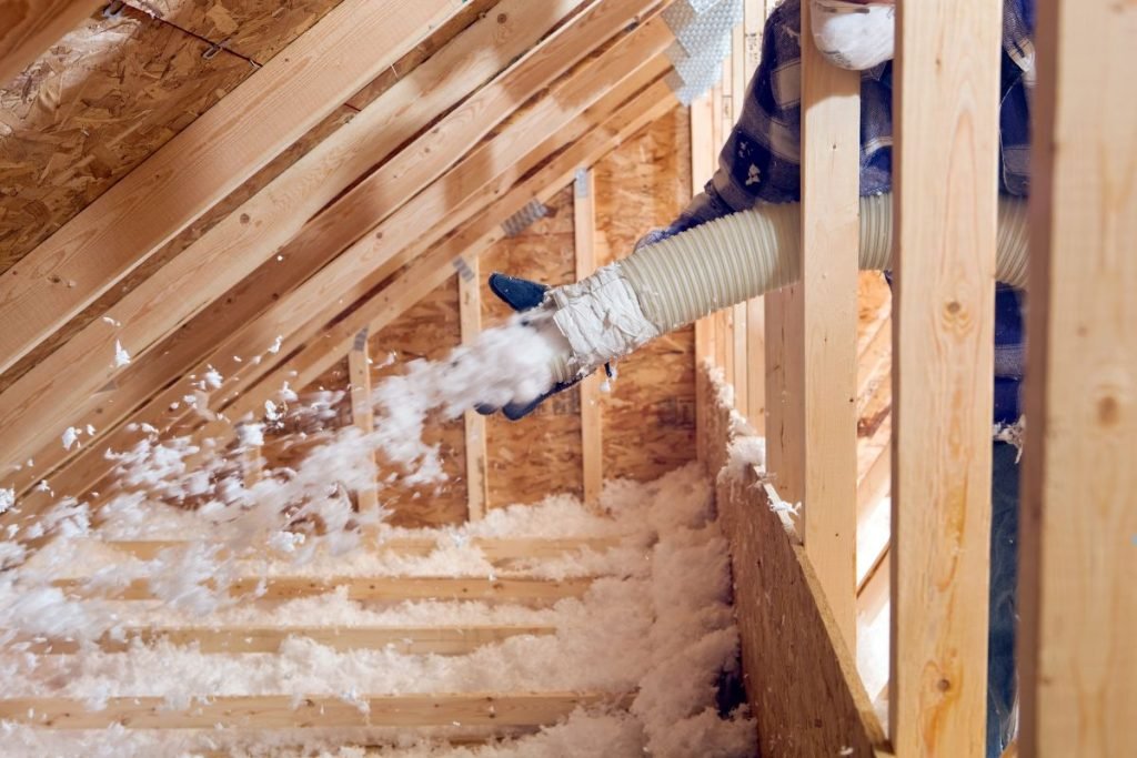 A man operates a vacuum to extract insulation from a home during an insulation installation service.