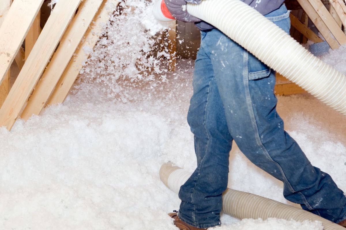 A man vacuums snow from an attic, demonstrating a cellulose insulation installation service.
